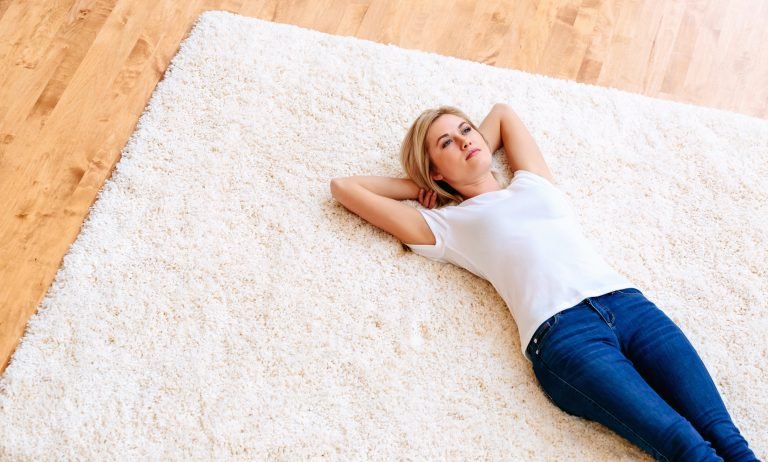 Young woman lying down on carpet